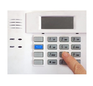 Panel de control de alarma con botones y dedo presionando uno de los números
